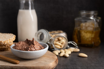Homemade organic vegan chocolate spread, made of almonds, honey and cacao. With a jar of rice milk