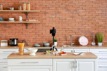 Prepared pasta with vegetables and professional photo camera in kitchen