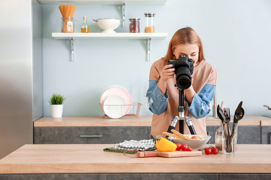 Young photographer taking picture of vegetable salad in kitchen