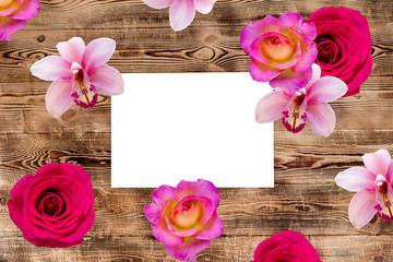 Wooden background with bright flowers and a white frame for inscription