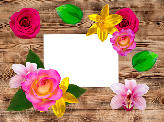 Wooden background with bright flowers and a white frame for inscription