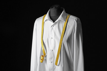 Mannequin with custom tailored shirt and measuring tape on dark background