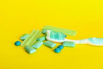 Tooth brush with paste and chewing gums on color background