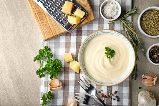 Bowl with tasty sauce and ingredients on grey background