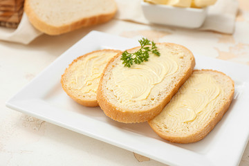 Plate with tasty bread and butter on table