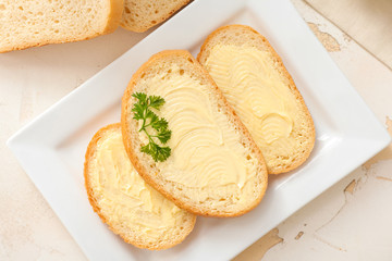 Plate with tasty bread and butter on table