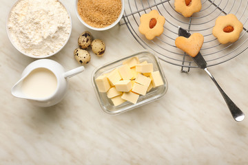 Bowl with fresh butter and ingredients for cookies on table