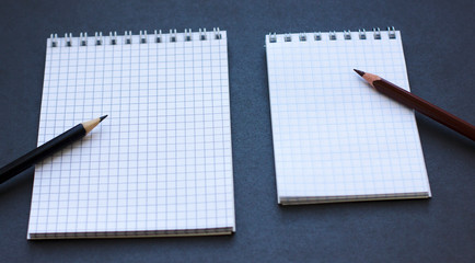 Два блокнота и карандаши на черном фоне