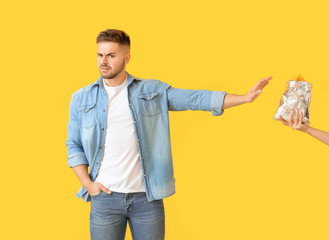 Handsome young man rejecting tasty potato chips on color background