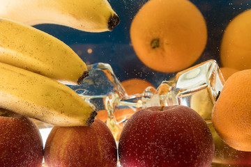 Glass bottle under water and surrounded by fruit. fruit still life.
