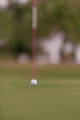Golf ball sitting close to the hole