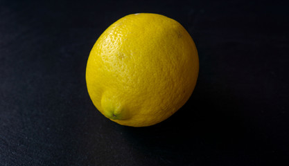 a yellow lemon in front of a black background