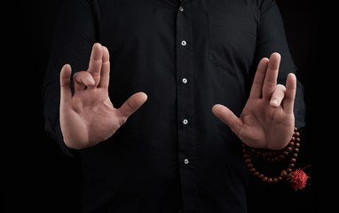 hand of an adult male shows mudra on a dark background