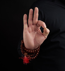 hand of an adult male shows om mudra on a dark background