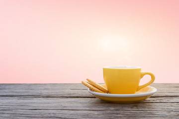 A cup of hot espresso coffee mugs placed with cookies on a wooden floor with pink background,coffee morning