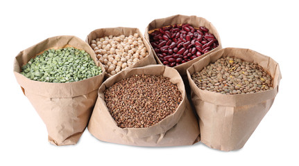 Different types of legumes and cereals in paper bags on white background. Organic grains
