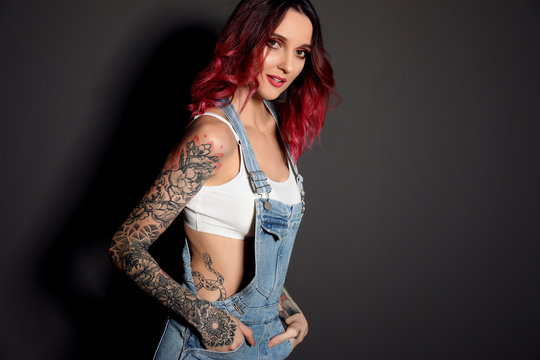Beautiful woman with tattoos on body against black background. Space for text
