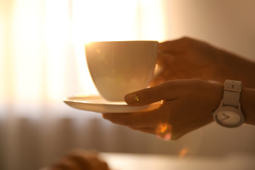 Woman holding cup of drink on blurred background, closeup. Lazy morning