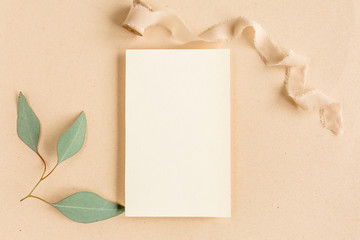 Mockup invitation, blank greeting card and green leaves eucalyptus. Flat lay, top view.