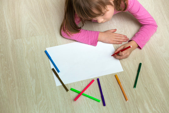 Cute child girl drawing with colorful pencils crayons on white paper. Art education, creativity concept.