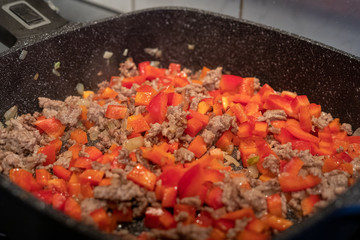 Raw minced meat with onions and peppers in a frying pan