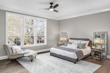 Beautiful bedroom in new luxury home with large windows and area rug