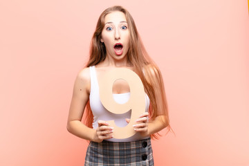yound blonde woman surprised, shocked, amazed, holding a number 9.