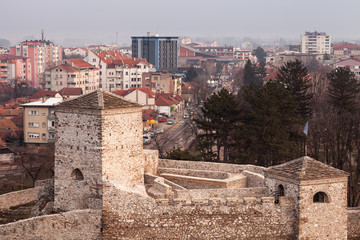 Fototapeta na wymiar Beautiful panorama of Pirot cityscape, with foreground ancient fortress Momcilov grad and city buildings and houses in the background during cloudy, cold winter day