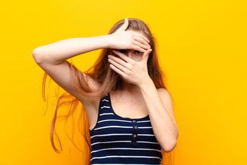 yound blonde woman covering face with both hands saying no to the camera! refusing pictures or...