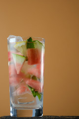 Watermelon cocktail with mint on a orange  background with ice. Refreshing summer cocktail.