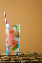 Watermelon cocktail with mint on a orange  background with ice. Refreshing summer cocktail.