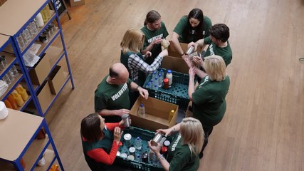 Food Bank volunteers help to sort food for hungry people and with social issues. Aerial View. Looking down from above, - Powered by Adobe
