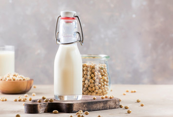 Soy milk and soy bean on gray table. Non-dairy milk concept. Vegan drink. Copy space