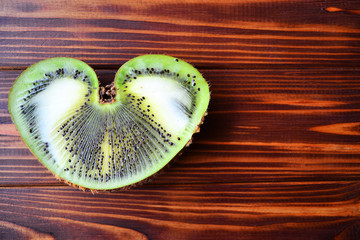 Imperfect kiwi on a wooden background. Ugly fruit, copy space.