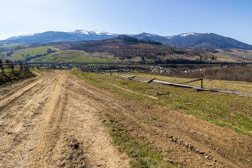 rural landscape in spring.  mountain ridge in the distance with snow capped tops and fields with...