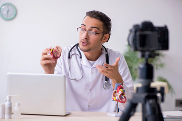 Young male doctor cardiologist recording video for his blog