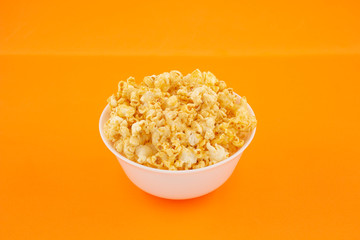 Popcorn in a bowl on an orange background close-up, horizontal frame