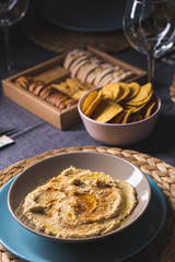 Tasty hummus chickpea food sauce on a plate on a blue and grey fabrics dinner table on a black background