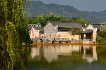 Fototapeta na wymiar Willow trees on the Longxi river with ancient bridge and Hui houses in Chengkan China