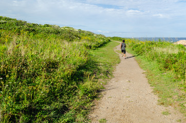 A boy traveling off the beaten path near the shoreline