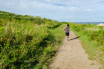 A boy traveling off the beaten path near the shoreline