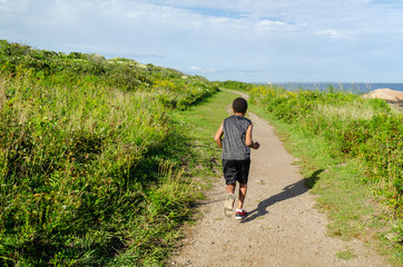 A boy traveling off the beaten path near the shoreline