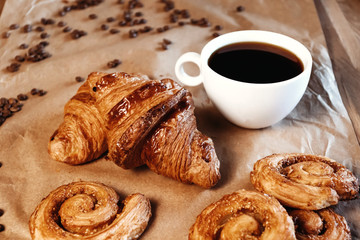 Cup of black freshly brewed coffee. Crispy croissant, breakfast in cafe.