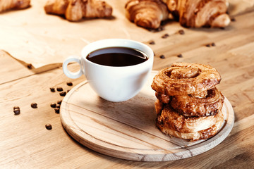 Cup of black freshly brewed coffee. Crispy croissant, breakfast in cafe.