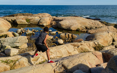 Young man on playing on the beach rocks