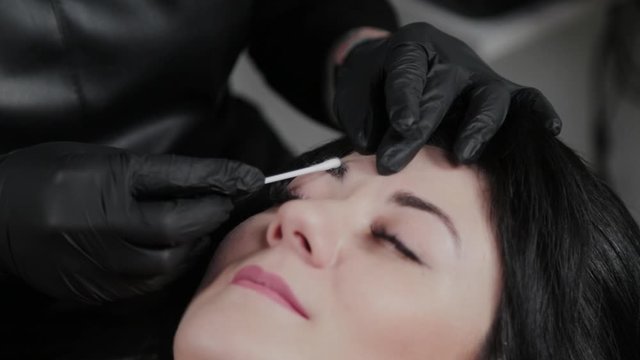 Professional permanent make-up artist apply anesthetic on the eyebrows of the client.