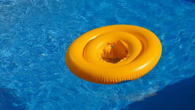 Floating ring on blue water of swimpool with waves reflecting in the summer sun