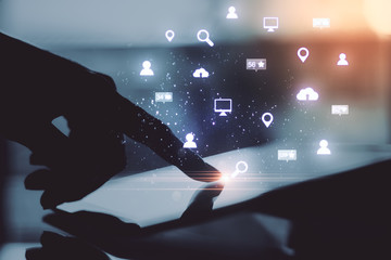 Hand holding digital tablet with glowing social network icons.