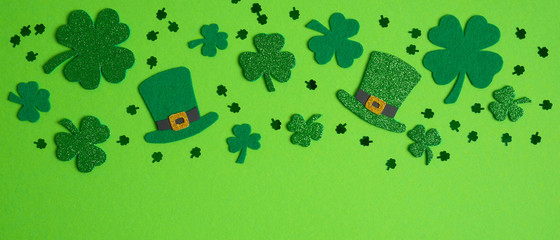 Frame border of shamrock, four leaf clovers and Irish elf hats on green background. Happy St....