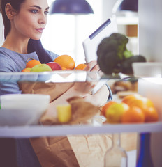 Smiling woman taking a fresh fruit out of the fridge, healthy food concept